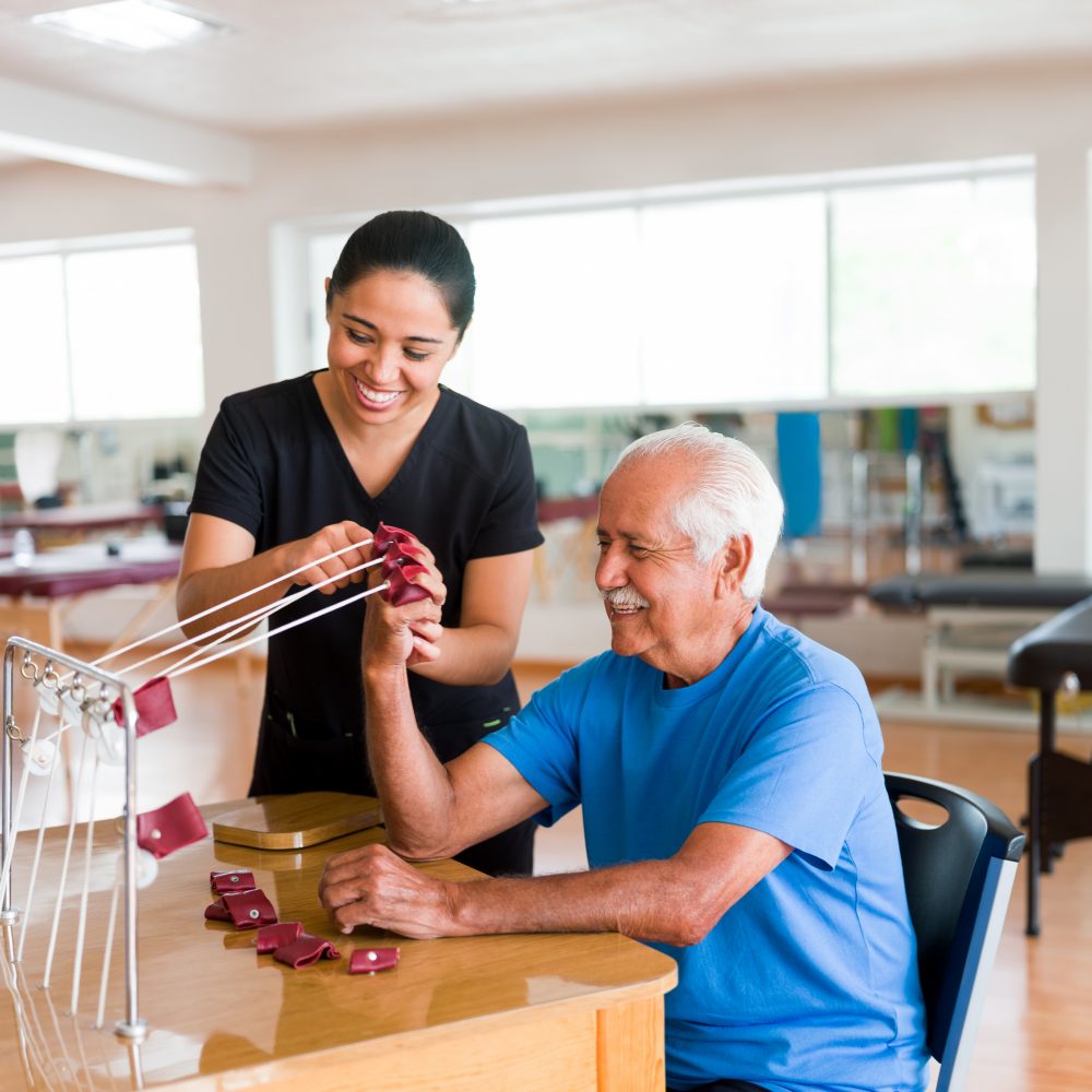 Happy senior man exercising hand with physical therapy device