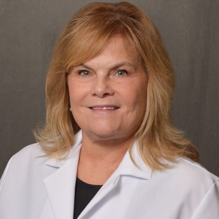 woman with medium length blonde hair in white lab coat