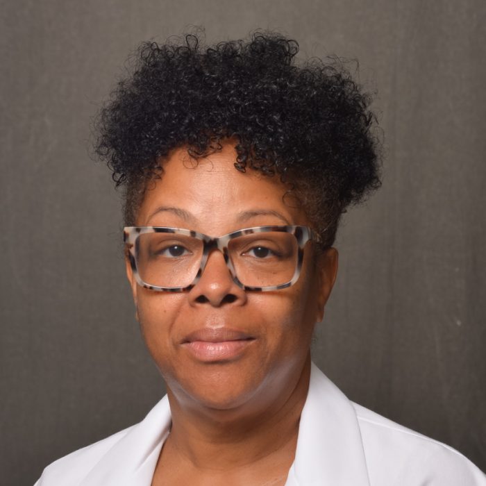 black female APN wearing glasses and white labcoat