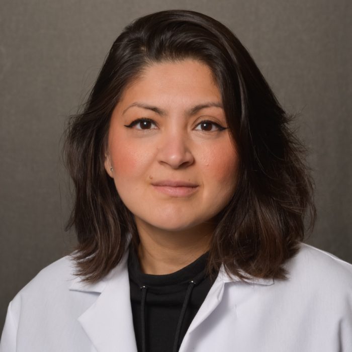 Female healthcare provider with children length brown hair, wearing a white lab coat