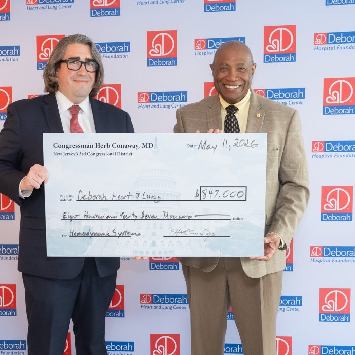 two men stand by side holding large check for $847,000