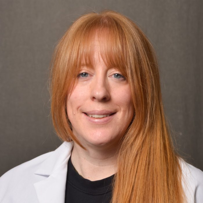 female nurse practitioner with long red hair and bangs