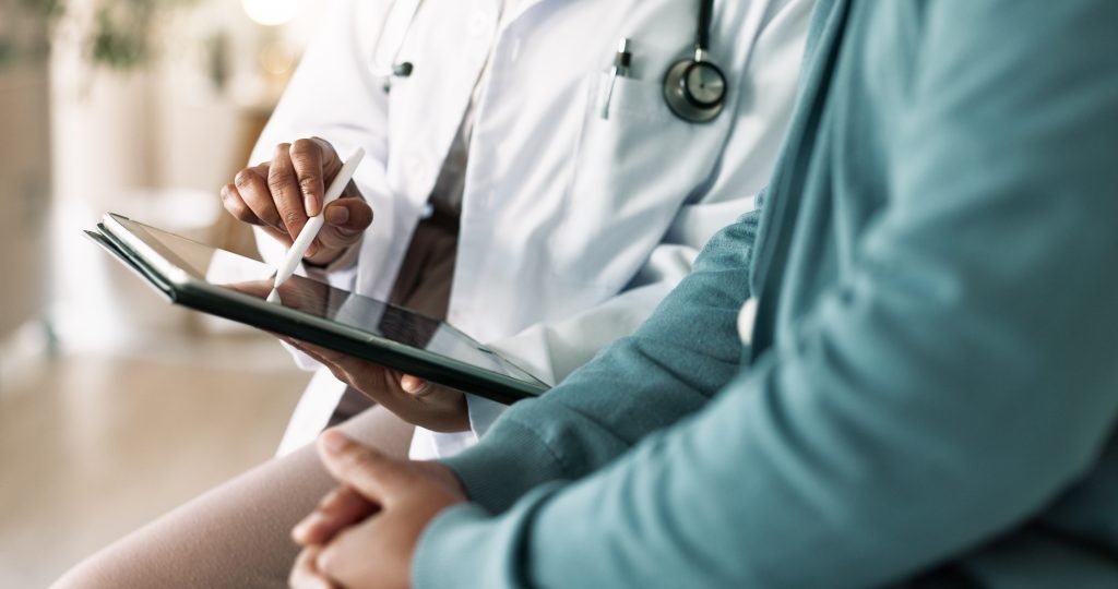 Doctor, hands and tablet with patient for consultation, medical advice or procedure at clinic. Closeup, healthcare employee and client with technology for health appointment or checklist at hospital