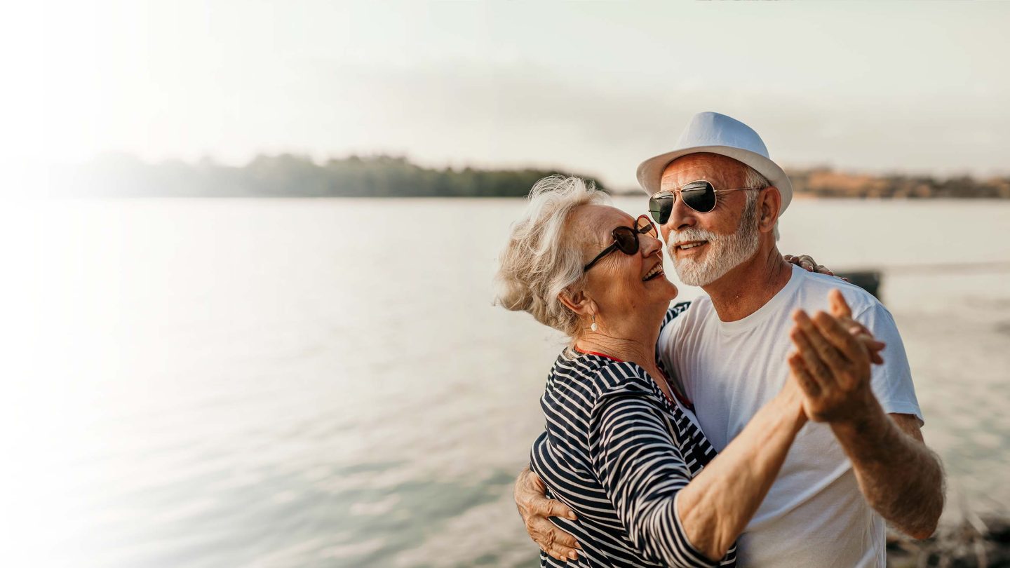 Senior couple dancing by water