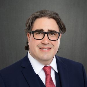 man wearing glasses and navy suit and red tie