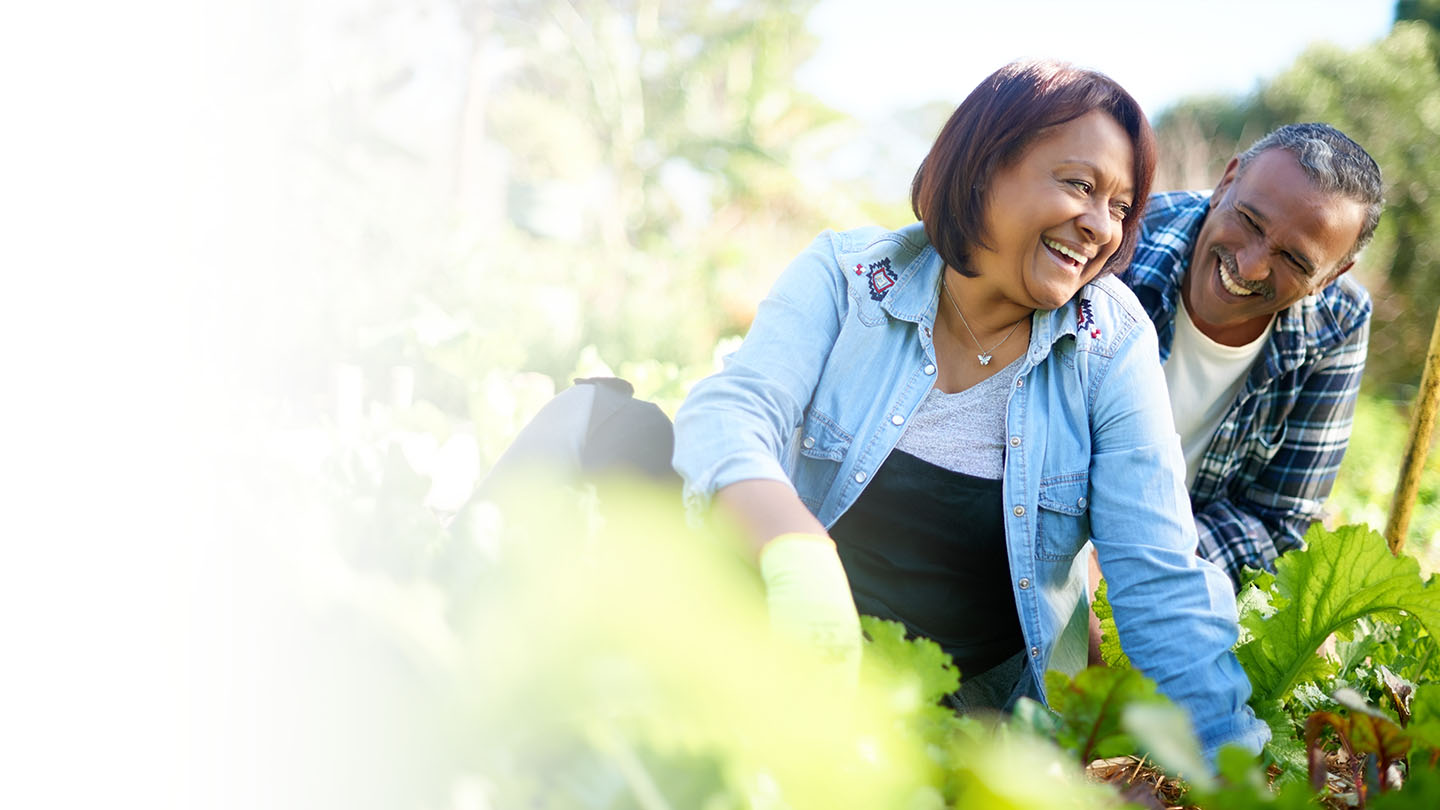older couple smiling and working in the garden together